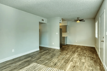 an empty living room and kitchen with a ceiling fan